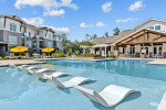 Luxury apartment community pool with lounge chairs and sunny umbrellas in Hammond, LA.