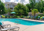 Outdoor pool area at Rose Heights Apartments in Raleigh with lounge chairs and greenery.