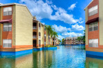View of the waterway and apartments at The Park at Veneto in Fort Myers, FL with blue skies and palm trees.