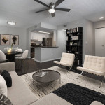 Modern apartment living room with ceiling fan, stylish furniture, and open kitchen layout in Pinellas Park, FL.