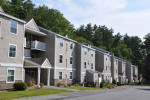 Exterior view of Stone Farm Apartments in Lebanon, NH, featuring modern architecture and lush greenery
