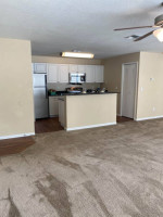 Spacious living area with modern kitchen and carpet at The Park at Catania apartments in Orlando.