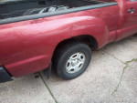 Close-up of a 2005 Toyota Tacoma showing its tire and side panel, highlighting its condition and features.