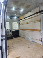 Interior view of a 2018 Ford Transit 250 with ample cargo space and new plywood flooring.