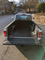 Rear view of a 2011 Ford Ranger pickup truck with a clean bed liner, parked on a street.