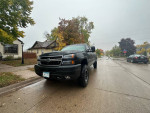 Front view of a 2006 Chevrolet Silverado 1500 parked on a street with trees in the background