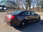 2015 Ford Taurus Police package in brown, parked with a bridge in the background, showing no dings and pristine condition.