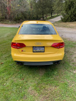 Rear view of a yellow 2010 Audi S4 parked on a grassy area, showcasing its sporty design.