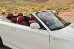 White BMW 135i Convertible with red interior parked in a scenic desert location