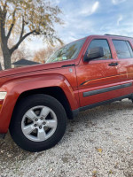2009 Jeep Liberty in burnt orange color with alloy wheels parked on gravel