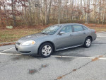 2009 Chevrolet Impala LS in excellent condition, gray color, parked in a clean outdoor area with trees.