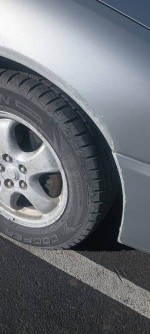 Close-up of the tire and side of a 2008 Ford Taurus SEL displaying new tires and minor imperfections.