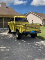 Yellow 1955 Chevy 3100 4x4 truck parked outside, showcasing classic design and upgraded features.
