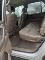 Interior view of a 2002 Toyota Sequoia showing spacious back seats with headrest TVs, well-maintained condition.