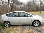 2005 Toyota Prius hatchback parked on gravel, showcasing its silver exterior and fuel-efficient design.