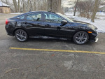 Side view of a black 2021 Honda Civic EX sedan parked, showcasing its sleek design and sporty wheels.