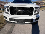 Front view of a white 2020 Ford F150 Lariat with a sleek design and black grille.
