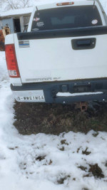Back view of a 2007 GMC Sierra 1500 Crew Cab parked in snowy conditions, showing the license plate and minor rust.