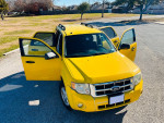 2011 yellow Ford Escape with open doors parked in a grassy area, showcasing its spacious interior.