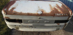 Rear view of a rusty 1972 BMW 3.0 CS with missing parts, showcasing barn storage condition.