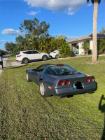 1990 Chevrolet Corvette in Steel Blue Metallic parked on grass, showcasing its classic design and powerful V8 engine.