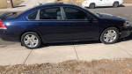 Midnight blue 2010 Chevrolet Impala parked on sidewalk with low mileage and well-kept exterior.