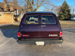 Rear view of a 1991 GMC Suburban in excellent condition parked outdoors.