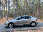 2012 Mazda 3 i Grand Touring in a forest setting, showcasing sleek design and reliability for daily driving.