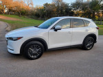 2019 Mazda CX-5 Touring parked on road, showcasing its sleek design and clean exterior.