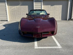 Front view of a restored 1980 Chevrolet Corvette in burgundy metallic color parked in a driveway.