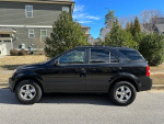 2009 Kia Sorento black SUV parked on street, showing its exterior and new tires, ready for a new owner.