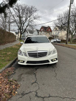 Front view of a 2010 Mercedes-Benz E-Class E550 in white, parked on a residential street.