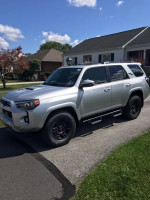 2023 Toyota 4Runner TRD Off-Road 4WD parked in front of a house, showcasing its sleek design and rugged features.