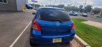Used blue Toyota Yaris hatchback with 88,000 miles, parked outside a dealership, showing some exterior wear.