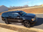 09 Chevrolet Suburban LTZ 4WD in black with chrome wheels parked on a road, showcasing its new paint job.