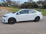 2016 Toyota Corolla S in white parked on a road, showcasing its sleek design and alloy wheels.