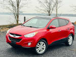 Red 2013 Hyundai Tucson Limited AWD parked near the waterfront showcasing its sleek design and alloy wheels.