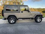 2005 Jeep Wrangler Rubicon Unlimited in Light Khaki Metallic, ideal for off-roading, parked on a driveway.