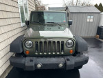 Front view of a 2007 Jeep Wrangler Sport with new tires and a backup camera parked at a residential area.