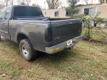 2002 Ford F150 truck with minor lift and potential transmission issues, parked in grass.