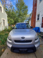 Front view of a 2011 Kia Soul parked in a driveway with trees in the background, showcasing its exterior features.