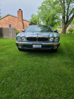 Front view of a 2003 Jaguar XJ8 in Zircon Blue parked on grass, showcasing its luxury design and condition.