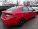 2014 Dodge Dart GT red sedan with alloy wheels parked in a lot, showcasing its sporty design and rear view.