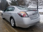 2012 Nissan Altima 2.5S in silver parked on a wet road, showcasing its sleek design and alloy wheels.