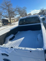 Back view of a 2014 Ford F250 Super Duty pickup truck with snow covering the bed.