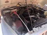 Engine compartment of a 2002 Jeep Wrangler Sahara with upgraded cold-air intake and battery.