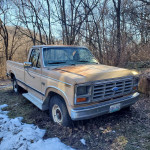 1984 Ford F250 classic truck in need of restoration, parked in the woods with a solid body.