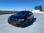 2014 BMW M5 parked on rooftop with clear blue sky, showcasing its sleek design and luxury features
