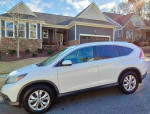 2014 Honda CRV EX-L AWD parked in front of a house, showcasing its clean white exterior and sleek design.