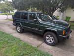 2001 Jeep Cherokee Sport RWD parked in driveway, showing green exterior and off-road tires